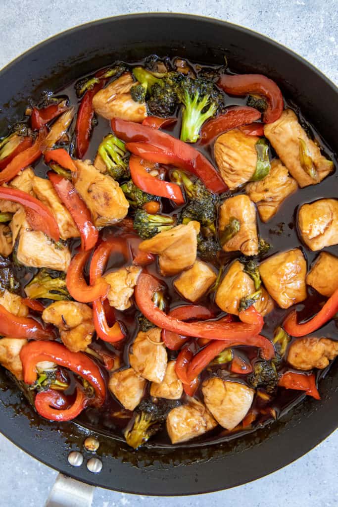 chicken breast, broccoli and red bell pepper tossed in a frying pan with hot honey frying sauce