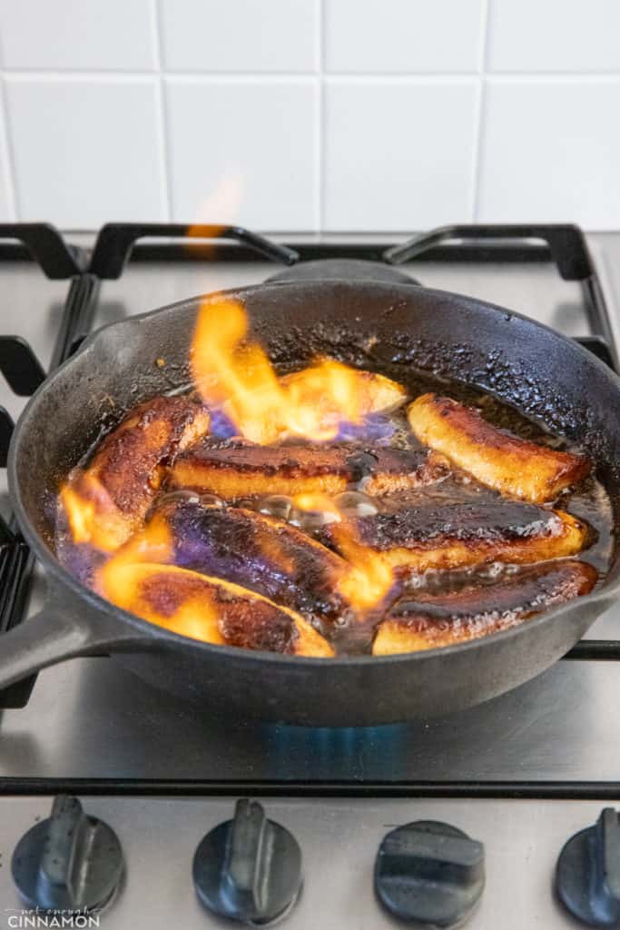 banana foster being lit on fire in a black skillet 