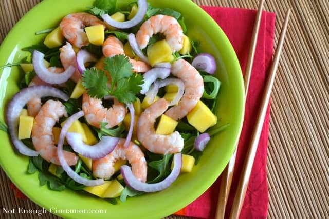 Mango, Shrimp and Arugula Salad on a green plate with chopsticks on the side