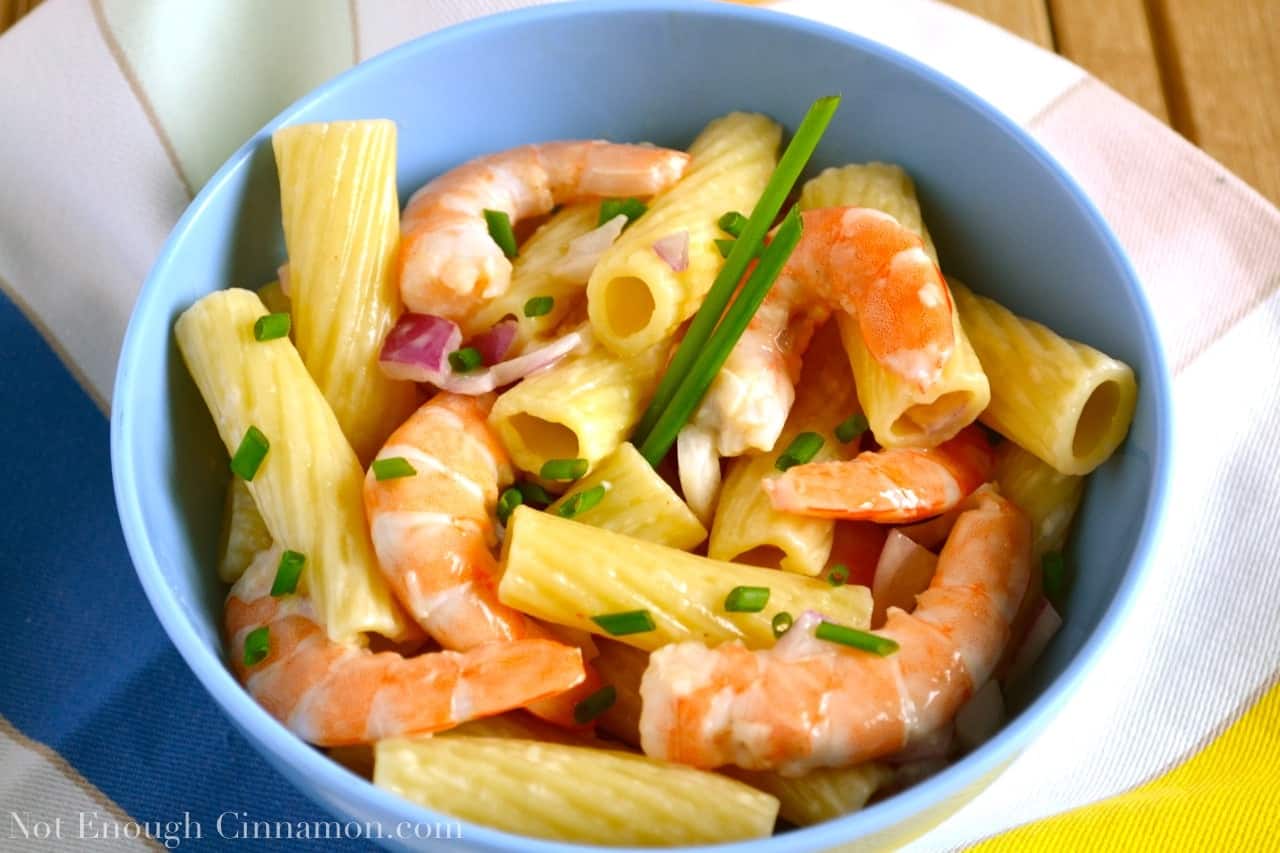 overhead shot of shrimp pasta salad with cooked shrimps, chopped red onions and chives in a light mayo dressing served in a blue bowl