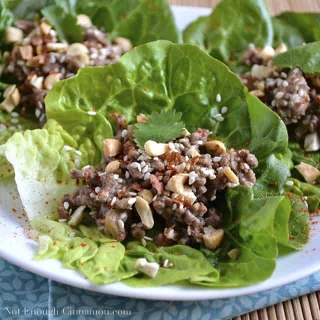 Asian Lettuce Wraps with Beef Filling sprinkled with sesame seeds and peanuts and arranged on a white plate