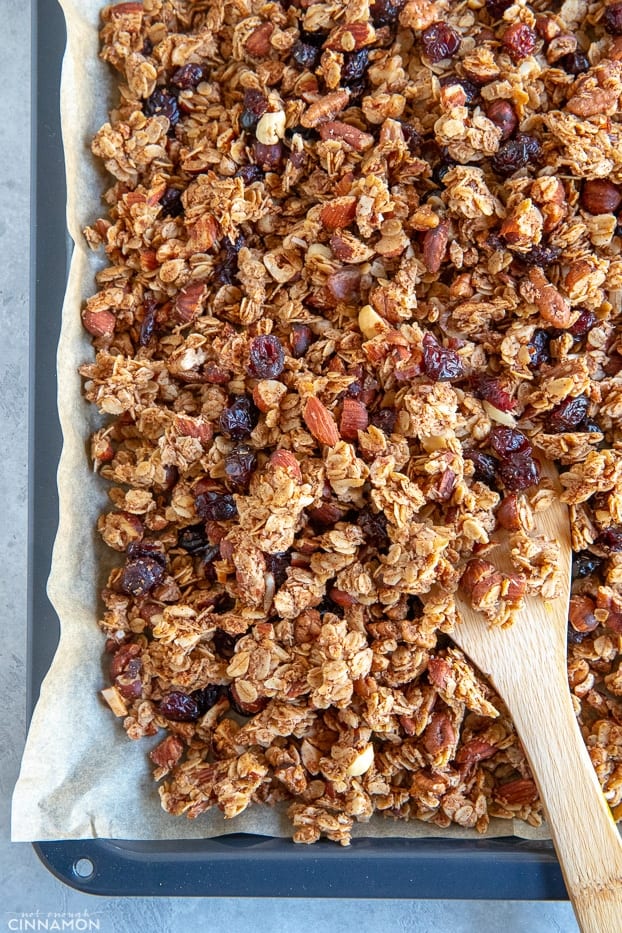 Homemade granola on a baking tray with a wooden spoon