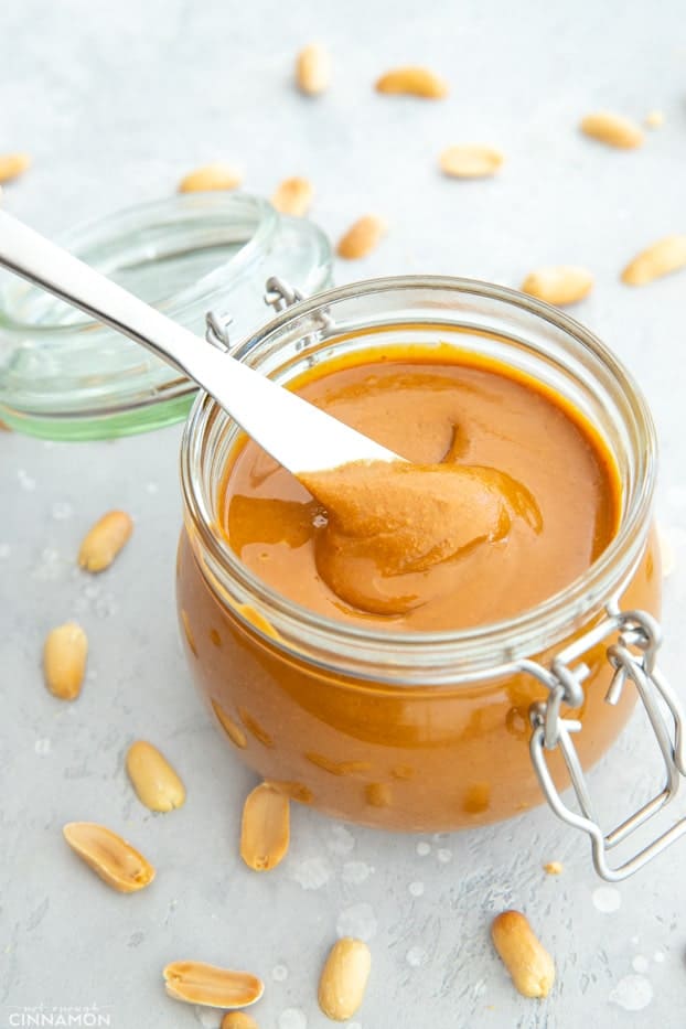 A jar of homemade peanut butter with a silver knife in it.
