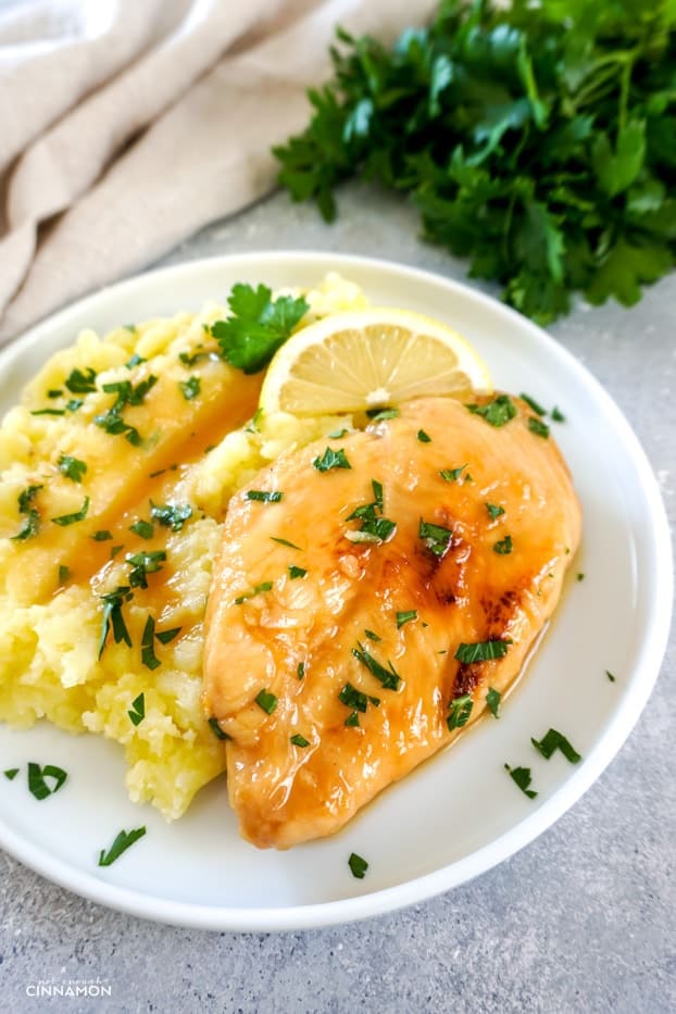 lemon basil chicken over mashed potatoes with a bunch of parsley and a towel in the background. 