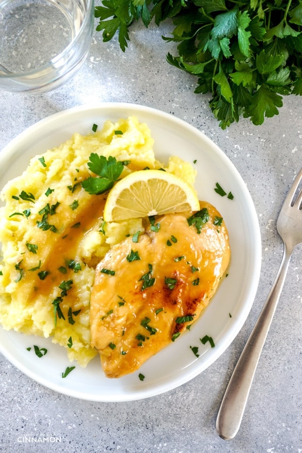 Lemon basil chicken breast with mashed potatoes on a white plate.