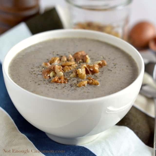 a white bowl of Skinny Cream of Mushroom Soup topped with chopped walnuts and freshly grated pepper
