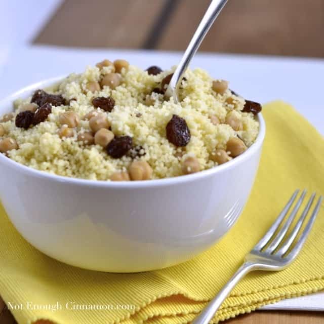 Couscous with Chickpeas and Raisins served in a white bowl on a yellow napkin