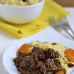 Lamb Tagine with Dried Apricots served on a white plate with a side of raisin-studded couscous