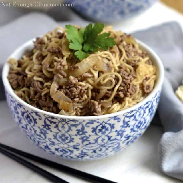 Asian Beef Noodles garnished with a cilantro leaf served in a Chinese blue and white noodle bowl with chopsticks on the side