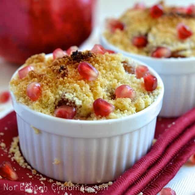 Side view of Pear and Pomegranate Crumble served in individual white ramekins sprinkled with pomegranate seeds