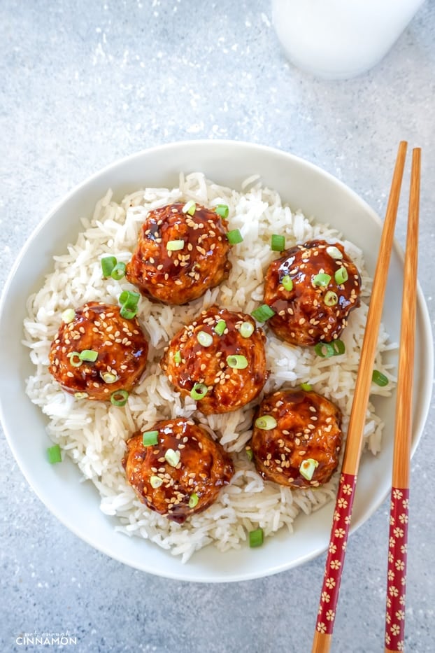 Asian glazed meatballs over rice in a bowl with chopsticks