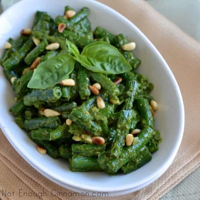Crispy Green Beans with Pesto served in a white oval dish with some fresh basil and pine nuts sprinkled on top