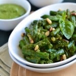 Crispy Green Beans with Pesto served in a white oval dish with some fresh basil and pine nuts sprinkled on top