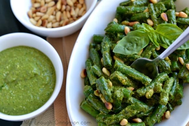 Crispy Green Beans with Pesto served in an oval dish with side dished of pesto and pine nuts
