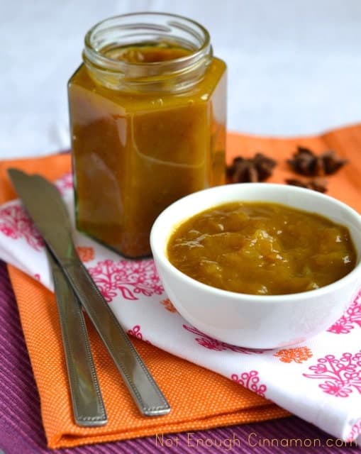 Mango Apple Chutney served in a small white bowls with a open jar of chutney and some whole spices in the background