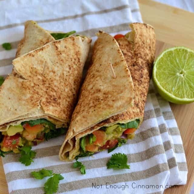 overhead shot of 2 Shrimp Avocado Wraps placed on a kitchen towel with a halved lime next to them