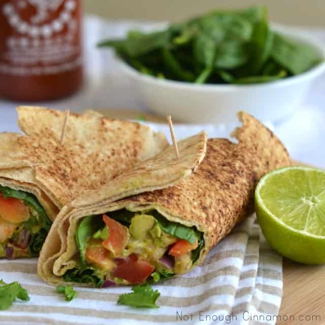 side view of 2 shrimp Avocado Wraps placed on a kitchen towel with a side salad in the background