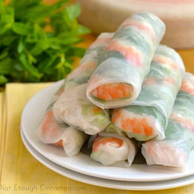 Fresh Vietnamese Spring Rolls stacked on a white plate with a side dish of dipping sauce