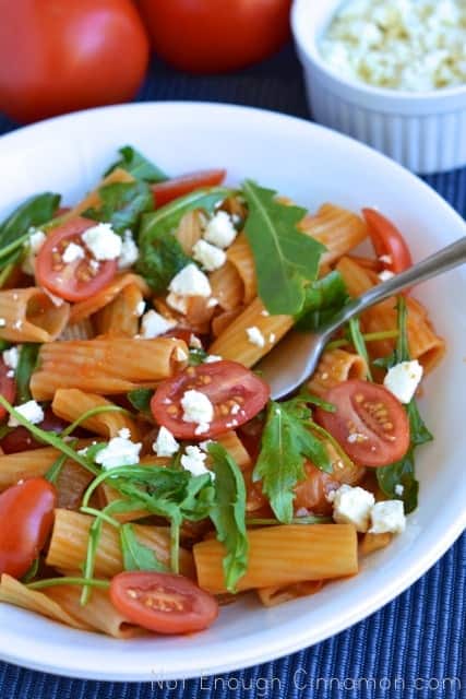 Pasta Risotto in a white bowl sprinkled with feta cheese, tomatoes and fresh arugula