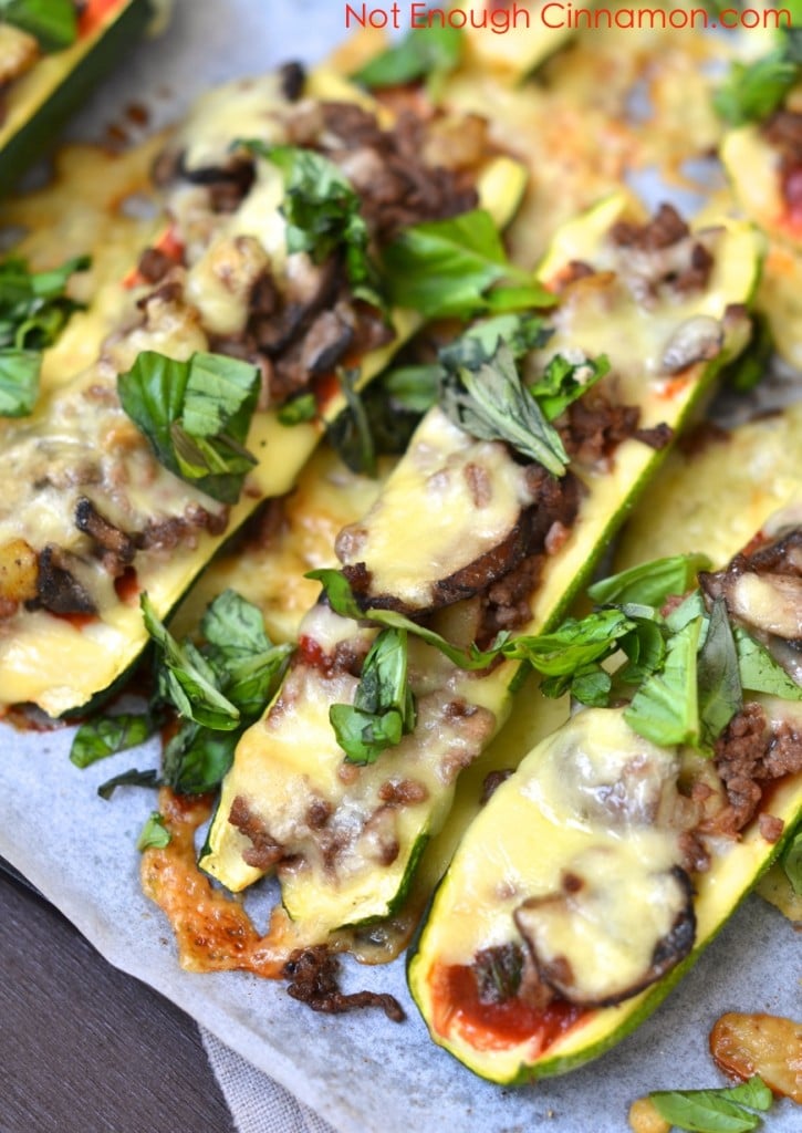  Cheesy Beef and Mushroom Stuffed Zucchini Boats sprinkled with fresh basil, served on a baking sheet