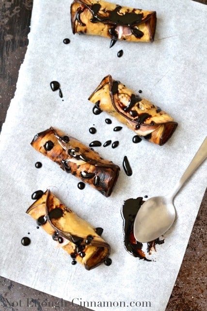  Prune and Prosciutto Eggplant Rolls drizzled with balsamic reduction on a piece of parchment paper