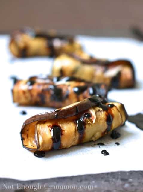  Prune and Prosciutto Eggplant Rolls drizzled with balsamic reduction on a piece of parchment paper