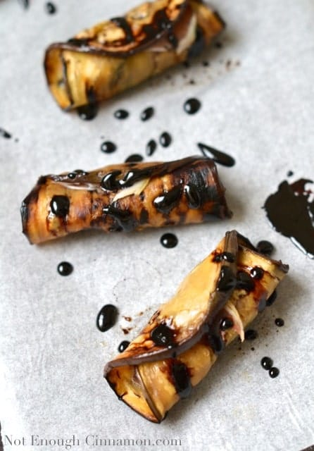 Prune and Prosciutto Eggplant Rolls drizzled with balsamic reduction on a sheet of parchment paper