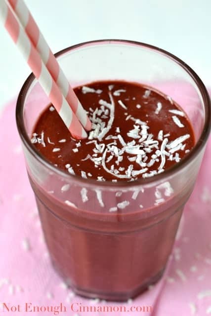 Raspberry Cinnamon Green Smoothie in a tall glass sprinkled with shredded coconut