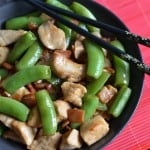 Bacon, Chicken and Snow Peas Stir-Fry served in a black bowl with some chopsticks on the side