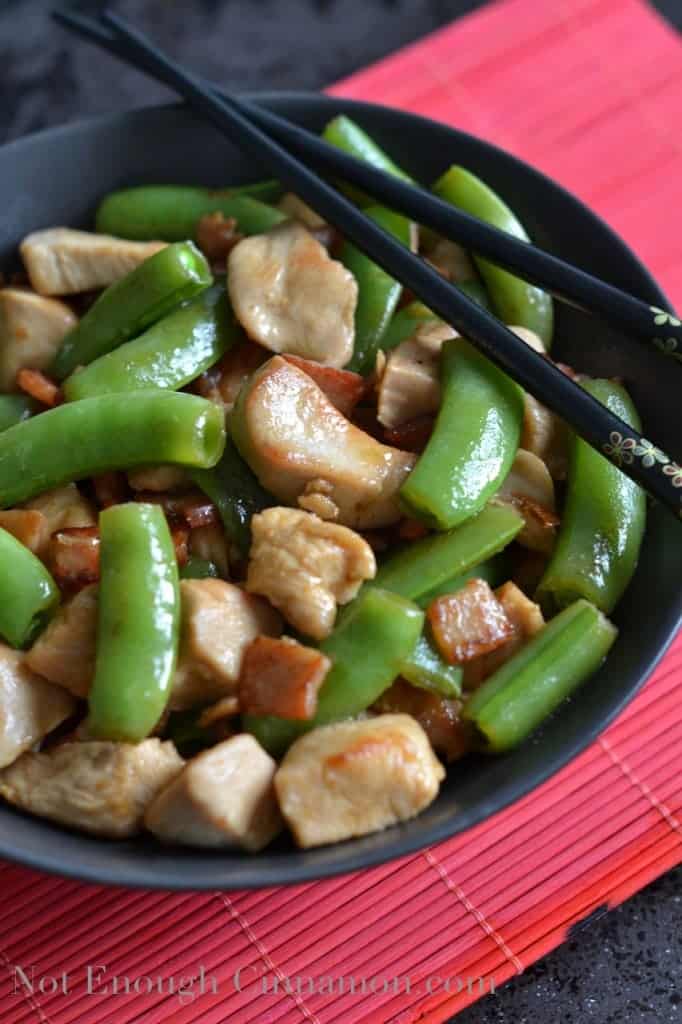 Bacon, Chicken and Snow Peas Stir-Fry served in a black bowl with some chopsticks on the side