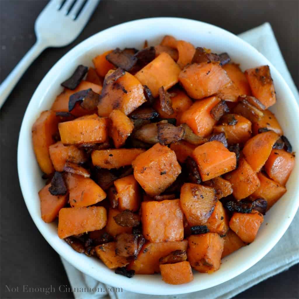 overhead shot of Bacon and Sweet Potato Skillet served in a small white bowl with a lot of crunchy bacon on top