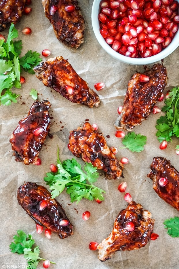 Baked chicken wings glazed with pomegranate glazed, arranged on a baking tray with coriander and pomegranate arils