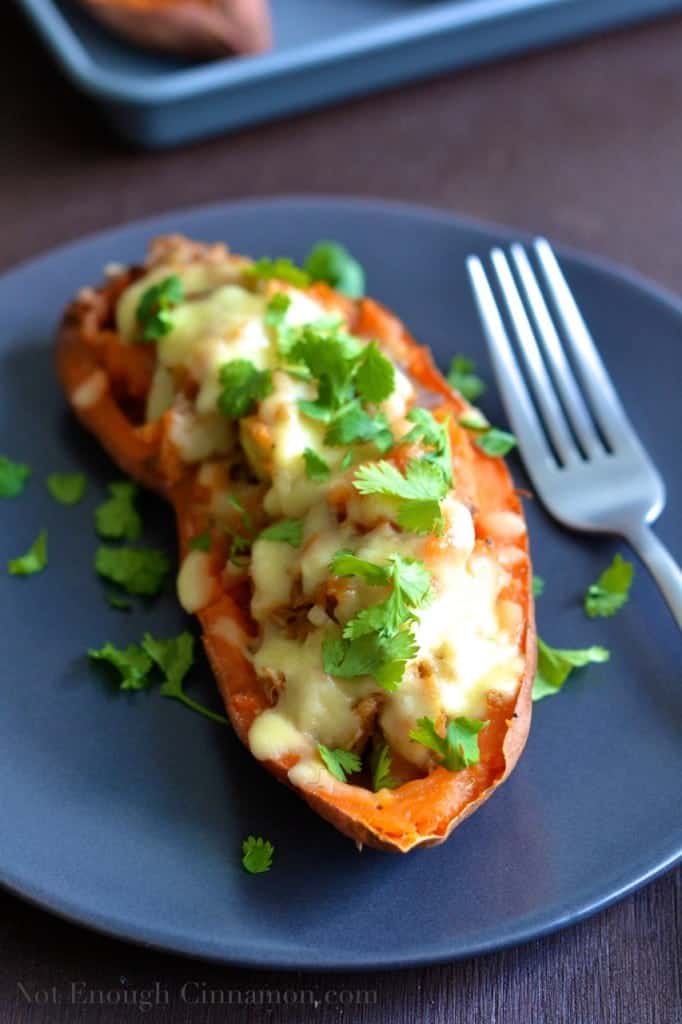 close-up of pulled pork stuffed sweet potatoes loaded with melted cheese and sprinkled with fresh cilantro