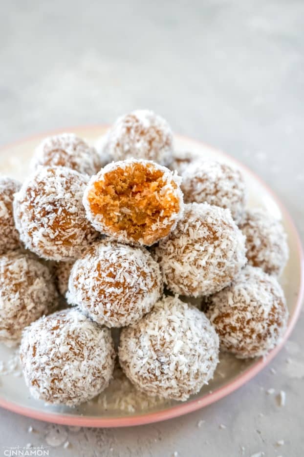 A pile of paleo energy bites on a white and pink plate, on a grey background