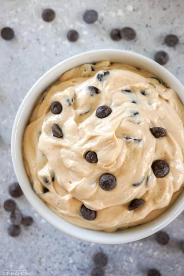 Overheat shot of peanut butter and chocolate chips dip in a white bowl, with chocolate chips around