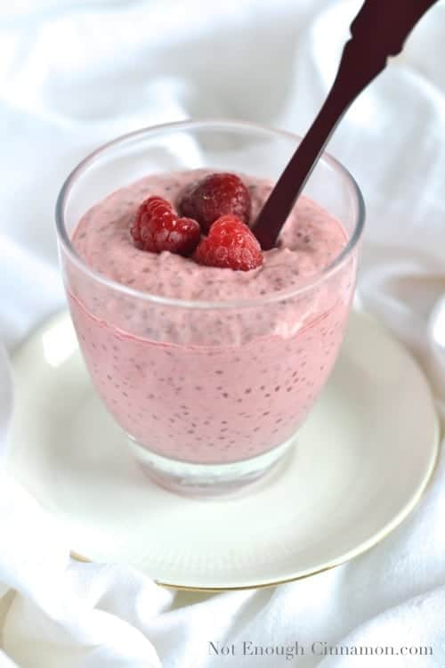 a spoon being dipped into a Vanilla Raspberry Chia Pudding served in a dessert glass 
