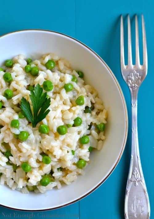 Overhead shot of Risotto Primavera aka Spring Risotto with green peas served in a white bowl with a fork on the side