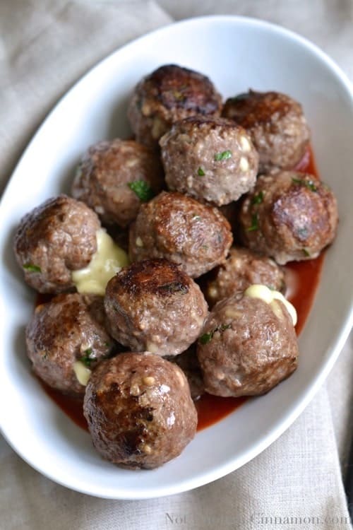 Easy Mozzarella Stuffed Meatballs served in an oval white dish with melted mozzarella oozing out of some meatballs