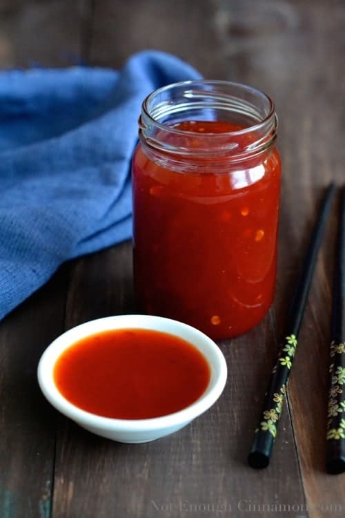 refined-sugar-free homemade chili sauce in a small white dish in front of a glass jar with more sweet chili sauce