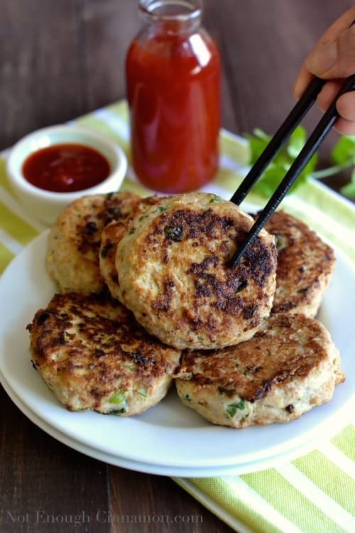 a pan-fried Paleo Thai Chicken Pattie on a plate with more patties being picked up with chopsticks - chicken patties recipe