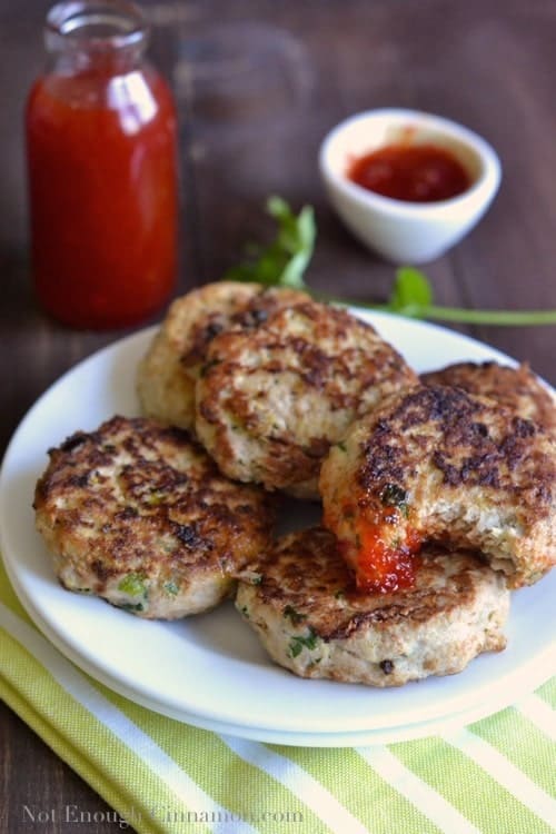 Paleo Thai Chicken Patties  served with homemade Sweet Chili Sauce on a white plate with some chili sauce in the background