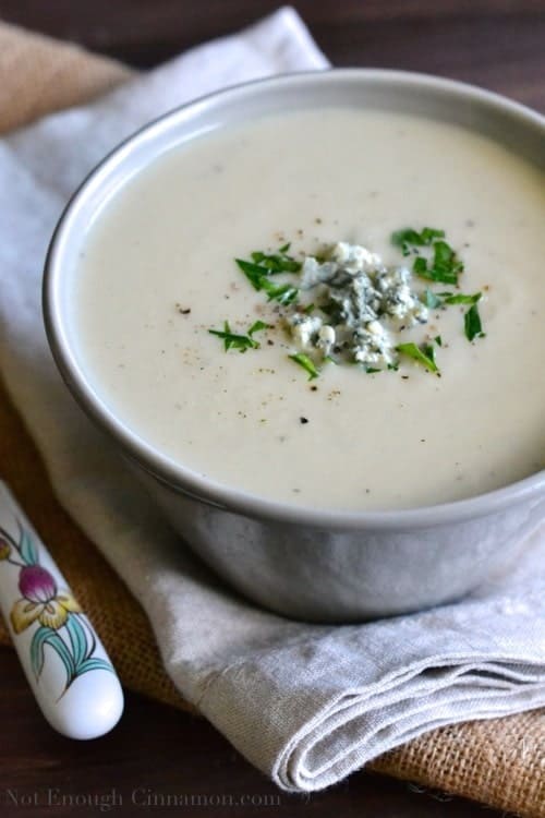 Skinny Cauliflower and Blue Cheese Soup made without cream, served in a soup bowl with crumbled blue cheese and chopped herbs sprinkled on top