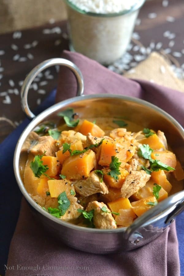 Easy Chicken and Pumpkin Curry served in an Indian curry bowl with some basmati rice in the background - pumpkin curry recipe