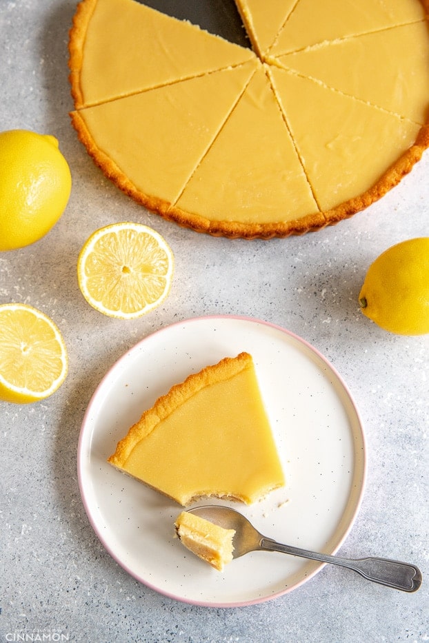 Paleo lemon curd tart with a slice on a white plate