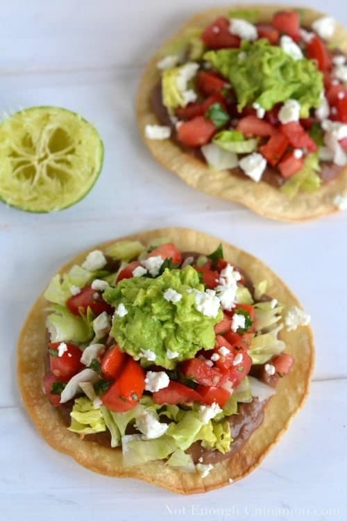 Overhead shot of Vegetarian Baked Tostadas topped with pico de gallo, mashed avocado and crumbled feta cheese