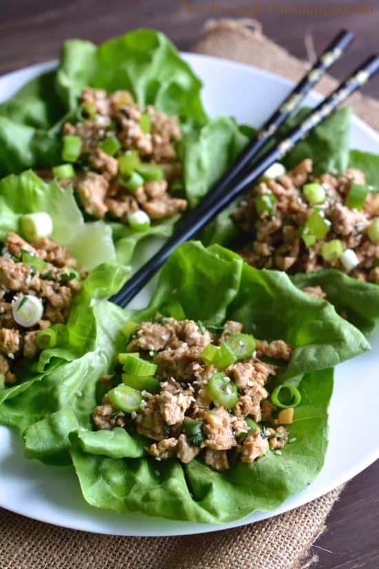 Healthy Asian Chicken Lettuce Wraps arranged on a big white plate along with a pair of black chopsticks
