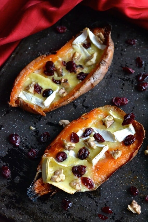 overhead shot of 2 Brie and Cranberry stuffed Sweet Potato Skins served on a black baking tray 