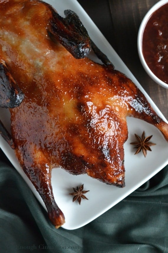 Easy Plum and Ginger Chinese Roasted Duck with crispy skin on a white plate served with a side dish of plum sauce