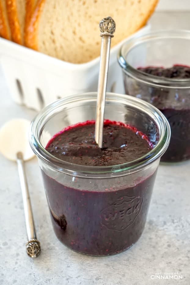 A jar of blueberry chia seed jam with bread slices in the background