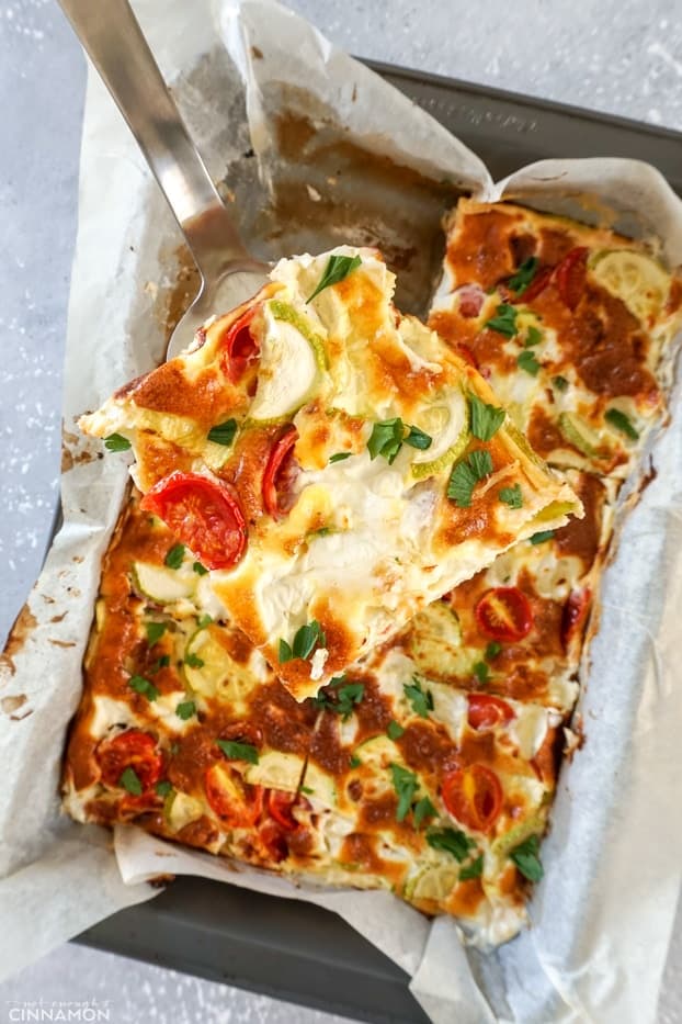 A piece of baked frittata held over a pan of frittata